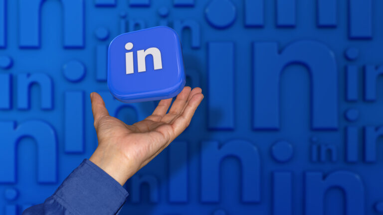 A square Linkedin badge falling on a male hand on unfocused blue background